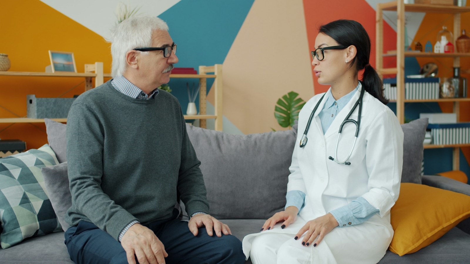 A clinician talking with an older man on a sofa at home