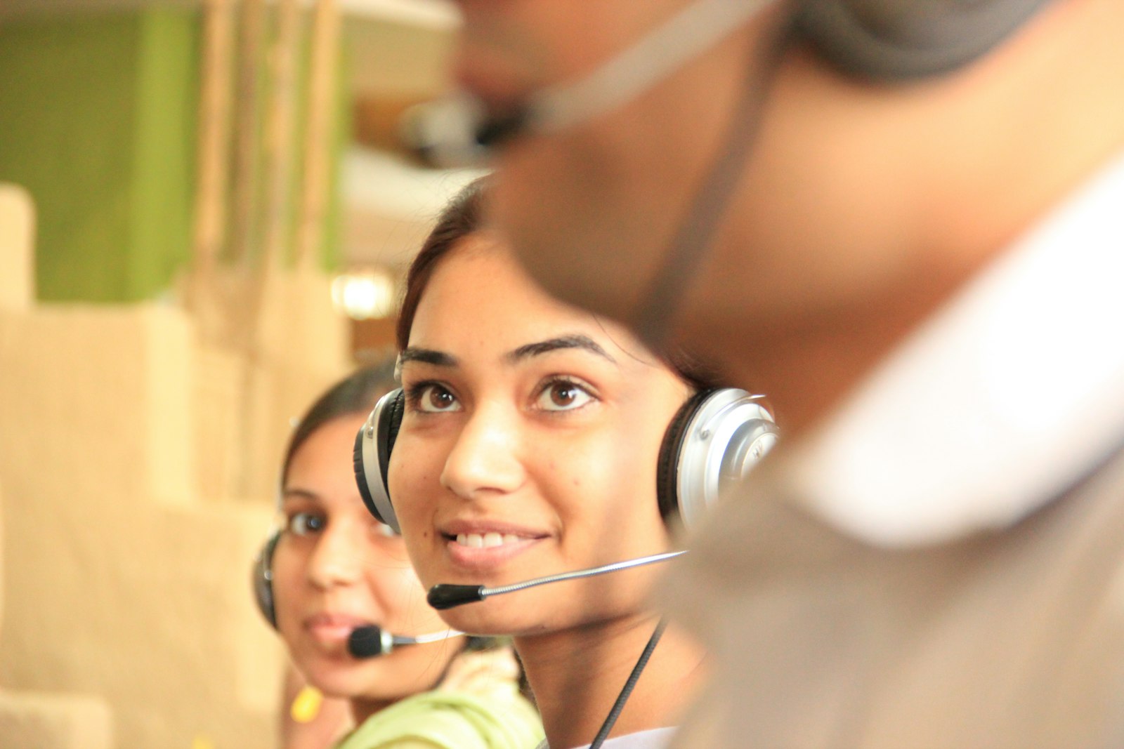 Two people wearing headsets in a bright office