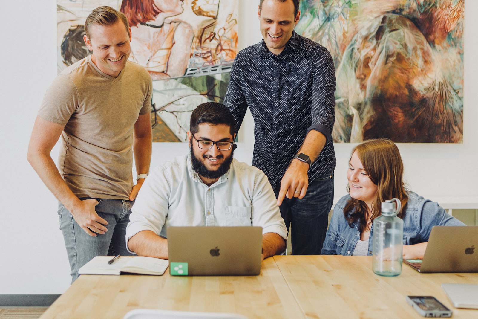 A small team smiling around a laptop